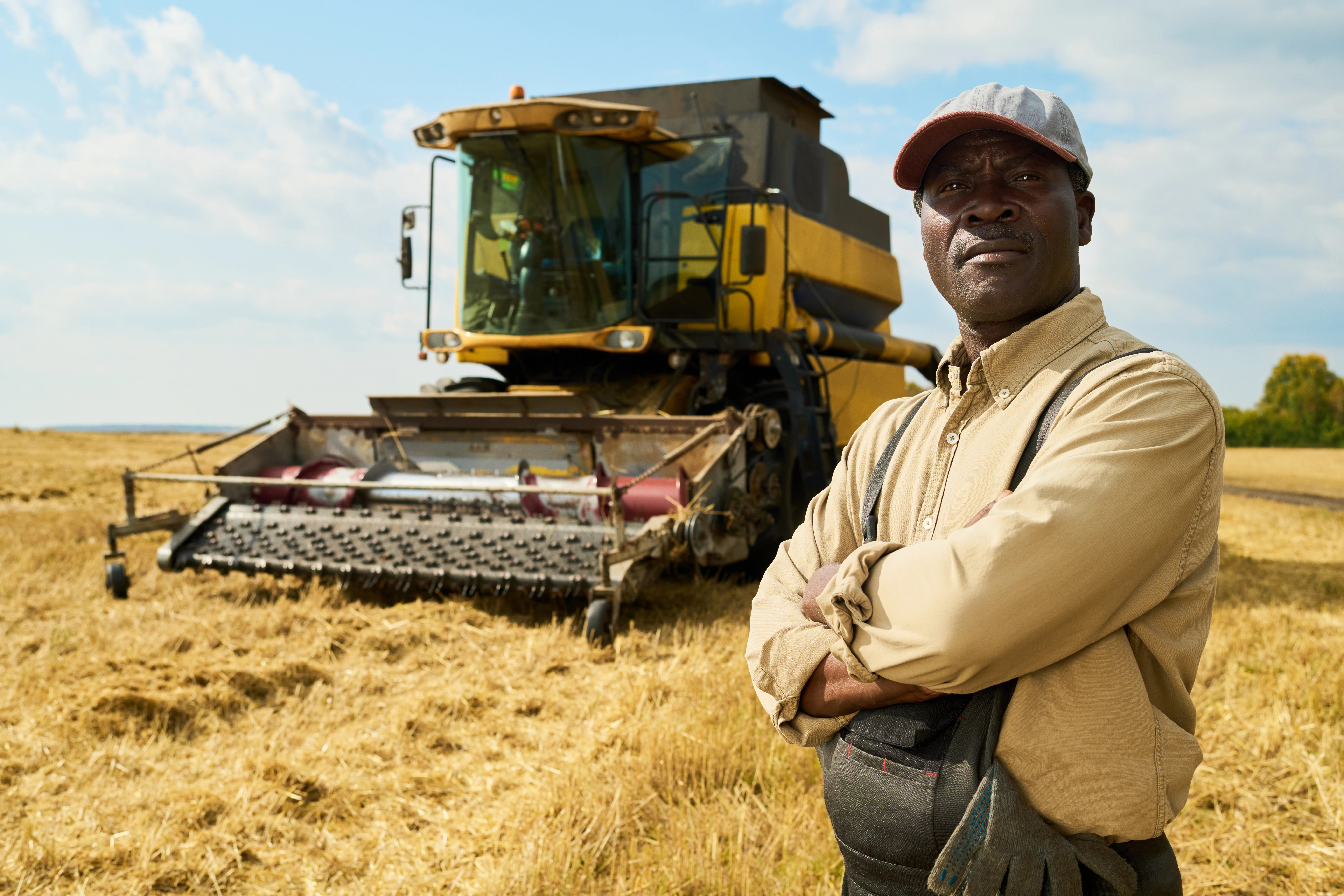 Confident farmer standing in front of a harvester in a Zimbabwean field